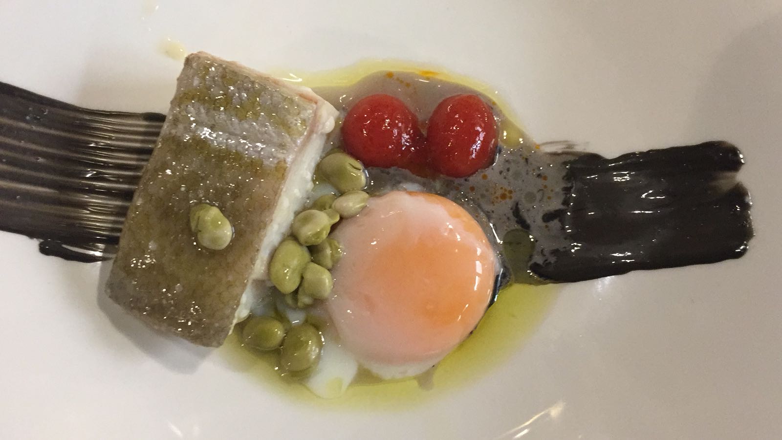 Bacalo confitado sobre base de ajo negro, esferas de tomate y habitas Mata – Restaurante La Platea (Granada)